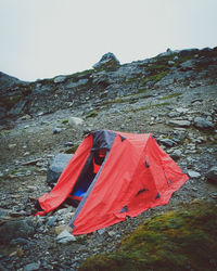 Tent on rocky mountain against clear sky