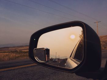 View of side-view mirror of car on road