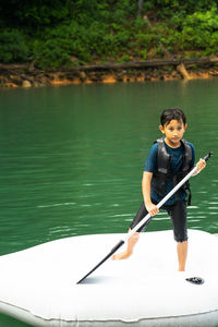 Young boy wearing life jackets paddling on an inflatable boat in kenyir lake, malaysia.