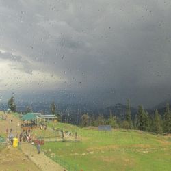 View of field against cloudy sky