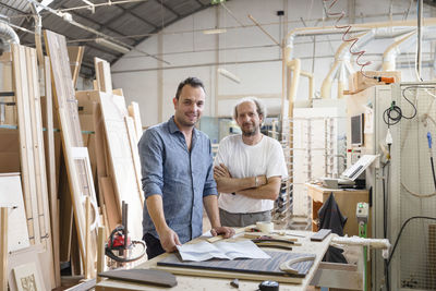 Smiling project manager standing by coworker in factory