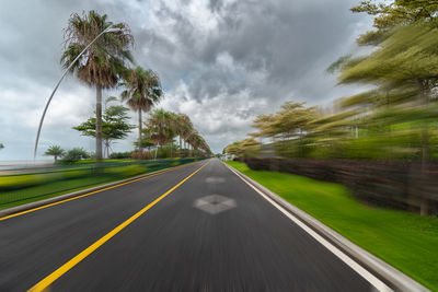 Road by trees against sky