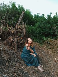 Portrait of young woman sitting on tree in forest