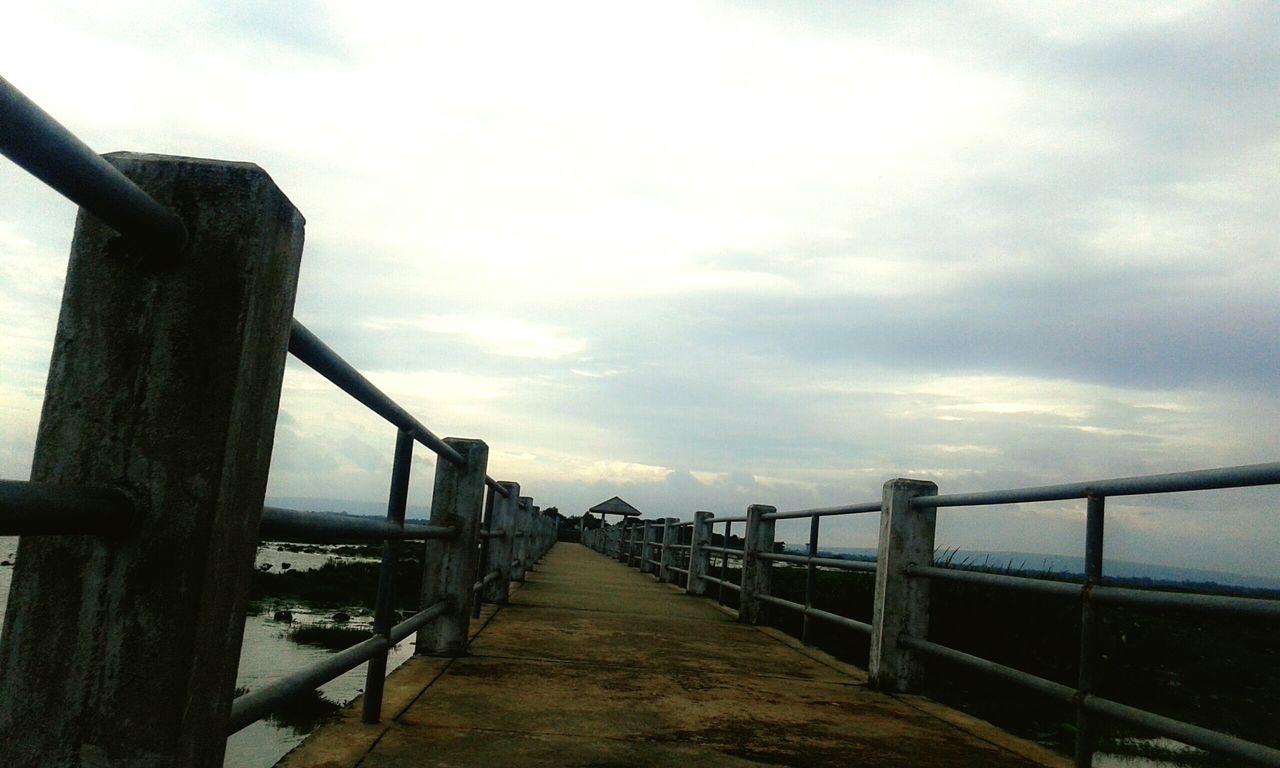 the way forward, railing, sky, pier, sea, built structure, water, cloud - sky, diminishing perspective, architecture, cloudy, wood - material, tranquility, horizon over water, weather, long, vanishing point, nature, tranquil scene, boardwalk