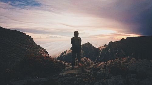 People standing on cliff at sunset