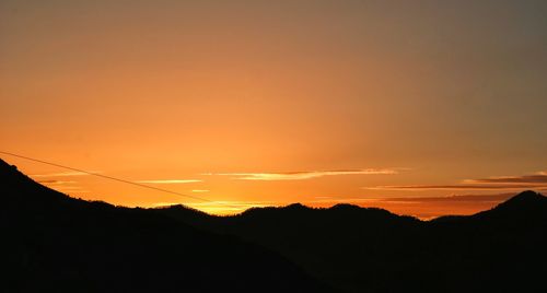 Scenic view of silhouette mountains against orange sky