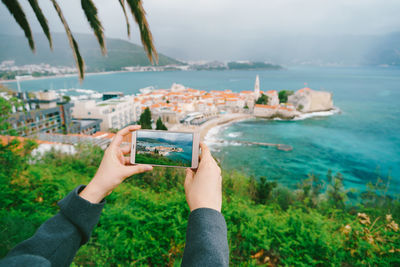 Midsection of woman photographing sea