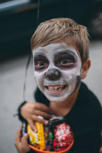High angle view of boy with face paint holding candies during halloween