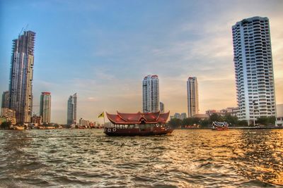 Ship in sea against modern buildings in city