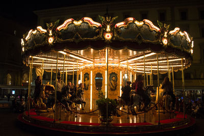 Illuminated carousel in amusement park at night