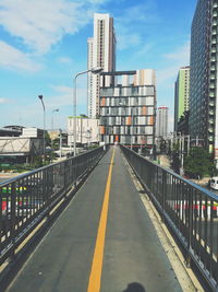 Road amidst buildings in city against sky