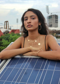 Portrait of woman standing on rooftop by solar panel