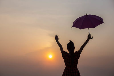 Silhouette woman standing by tree against sky during sunset