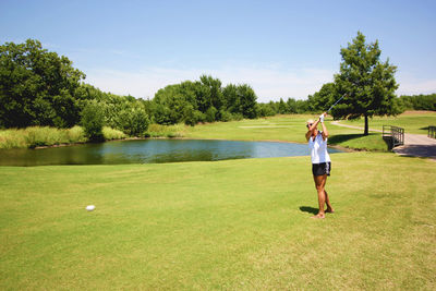 Full length of woman playing golf on field during sunny day