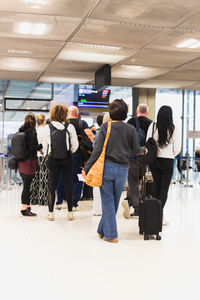 Woman with luggage standing in a line at airport.