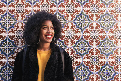 Smiling young woman standing against tiled wall