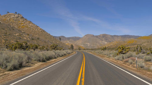 Empty road along landscape and mountains against sky