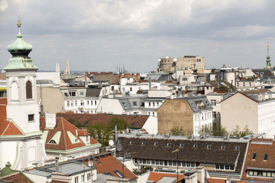 Houses in city against cloudy sky