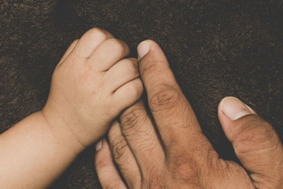 Cropped hands of child and parent on blanket 