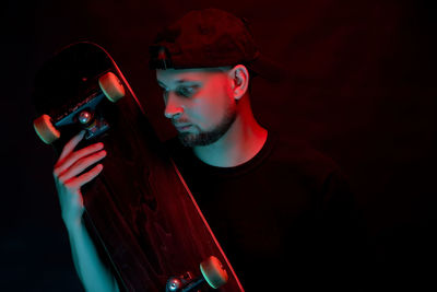 Portrait of young man holding camera over black background