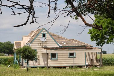 House and trees on field against sky