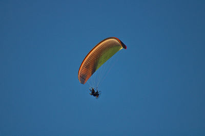 Low angle view of person paragliding against clear blue sky