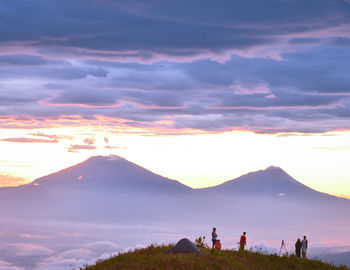 People on mountain against sky during sunset