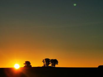 Silhouette trees against clear sky during sunset