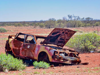 Abandoned car on field against sky