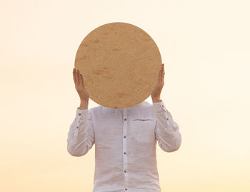 Midsection of woman wearing hat against yellow background