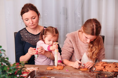 Mother and daughters preparing gingerbread cookies at home