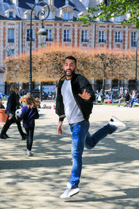 Portrait of smiling gay man running at place des vosges