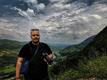 Young man standing on mountain against sky