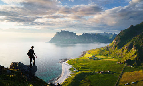 Rear view of man standing on mountain against sky during sunset