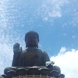 Low angle view of buddha statue against cloudy sky