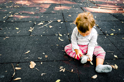 High angle view of girl playing with dry leaves