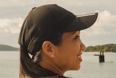 Portrait of woman wearing hat against lake