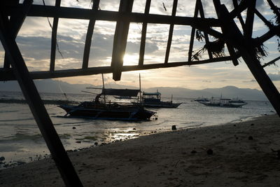 Sailboats moored on beach against sky during sunset