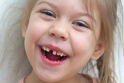 Girl with gap tooth laughing against wall