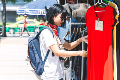 Side view of young woman with backpack shopping in city during sunny day