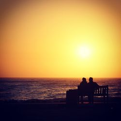 Silhouette of people in sea at sunset