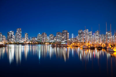 Illuminated cityscape against clear blue sky at night