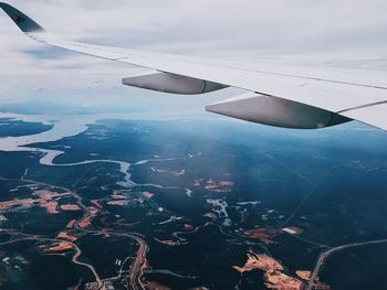 Aerial view of airplane wing over landscape against sky