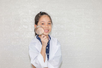 Portrait of smiling girl standing against wall