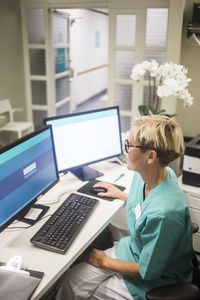 High angle view of mature female doctor working over computer while sitting in clinic