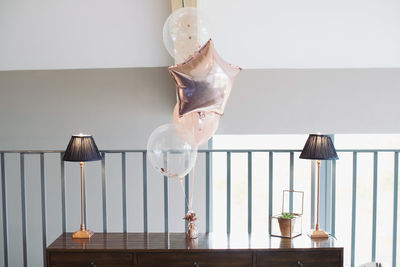 Close-up of electric lamp on table against wall at home