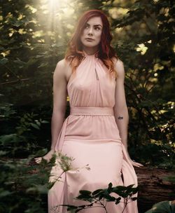 Portrait of beautiful young woman standing against trees