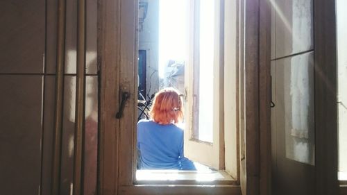 Woman seen through window on sunny day