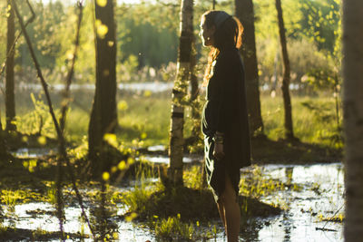 Side view of woman standing in lake at forest