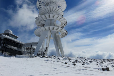 Snow covered communicatuons tower against sky
